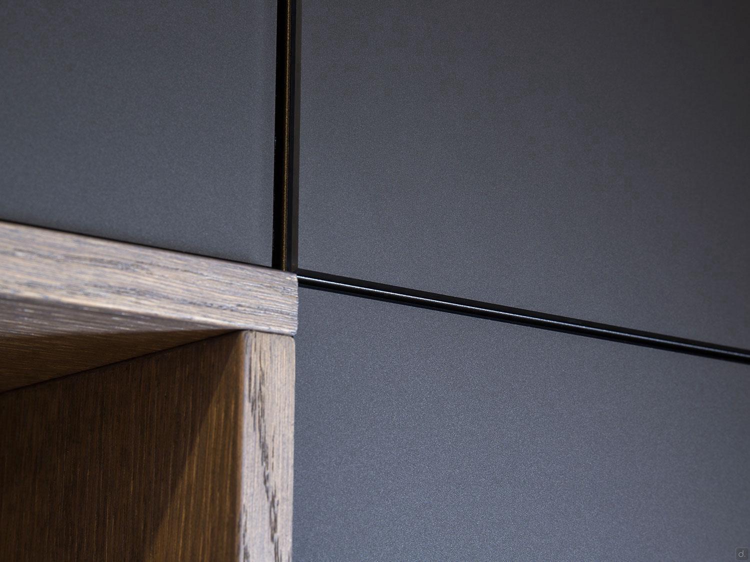 Close-up of a Modern Kitchens cabinet by ORDER Kitchen Furniture, featuring dark grey matte panels and a wooden section, showcasing the clean lines and sharp angles of minimalist custom kitchen design.