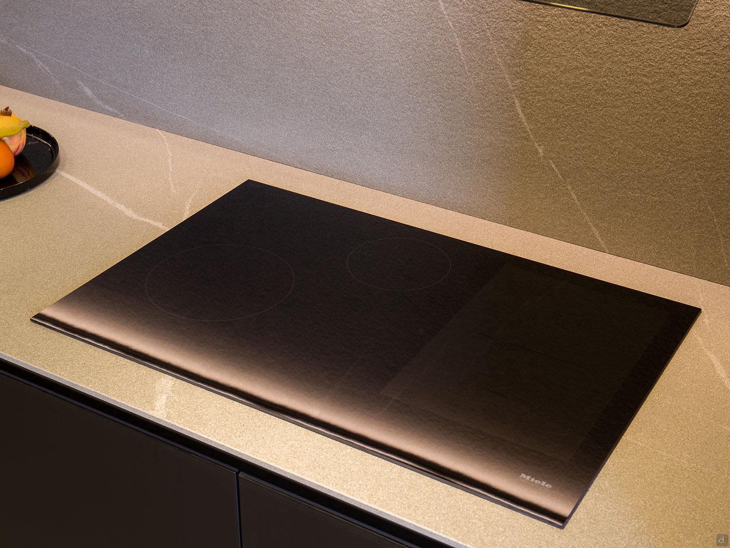 A sleek black induction cooktop from ORDER Kitchen Furniture’s Modern Kitchens line is installed on a beige countertop—perfect for minimalist spaces seeking seamless design and custom kitchen solutions.