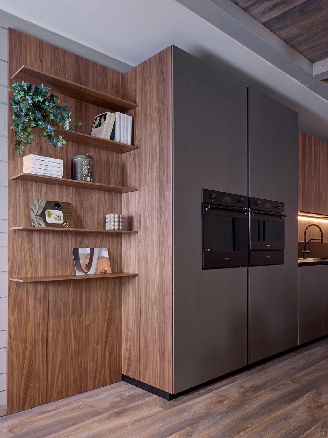 Modern Kitchens by Kitchen Furniture features wood paneling, open shelves for books and decor, sleek built-in appliances beside matte-finish cabinets, and warm lighting that highlights the right-side sink area.