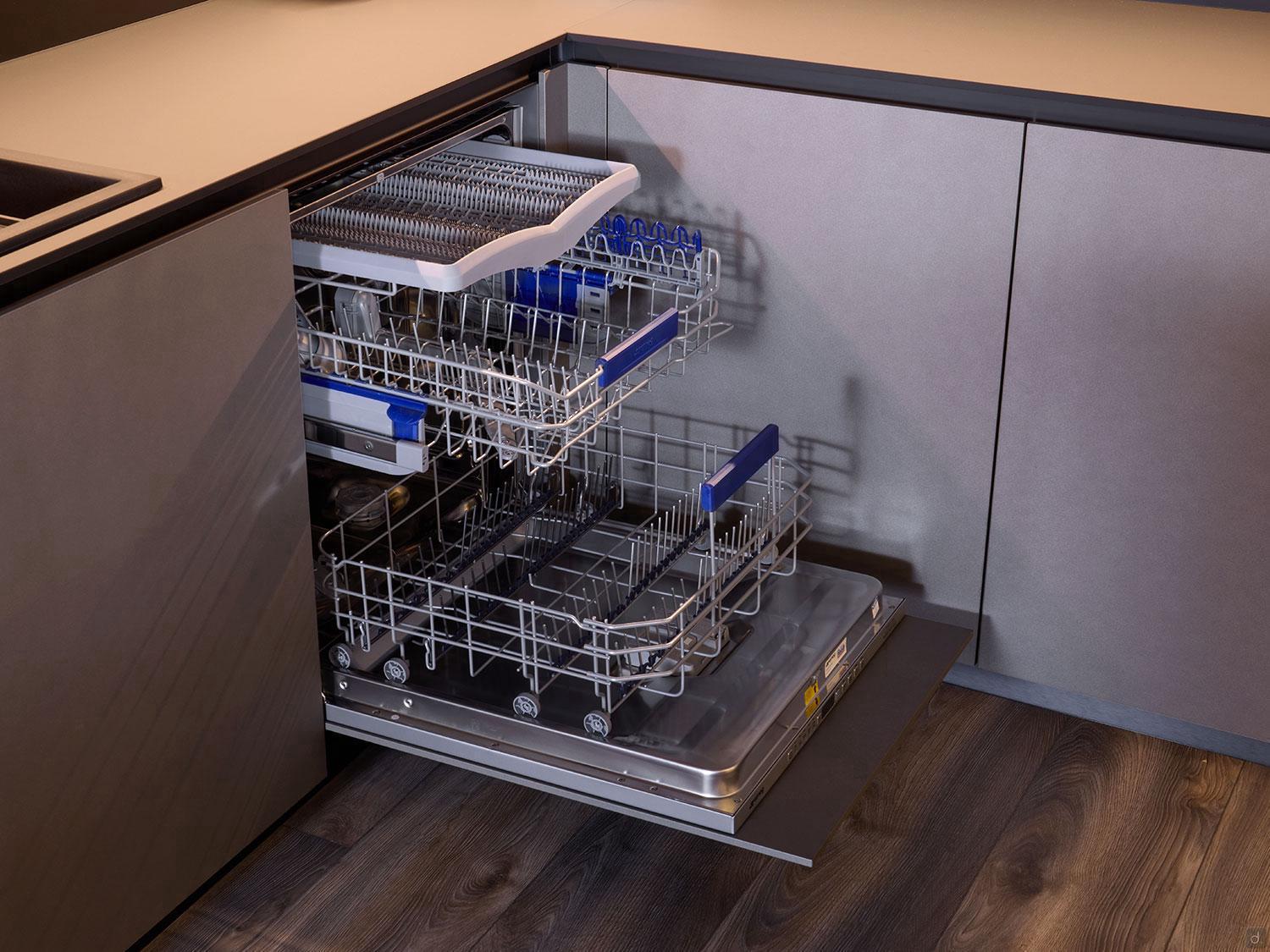 The Modern Kitchens built-in dishwasher by Kitchen Furniture features three empty racks and is displayed in a sleek kitchen with grey cabinets and dark wood floors—perfect for modern kitchens or custom kitchen furniture in Yerevan.
