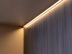 A warm white LED strip light illuminates smooth wood panels in a minimalist corner, creating a soft ambient glow—ideal inspiration for Modern Kitchens by Kitchen Furniture.