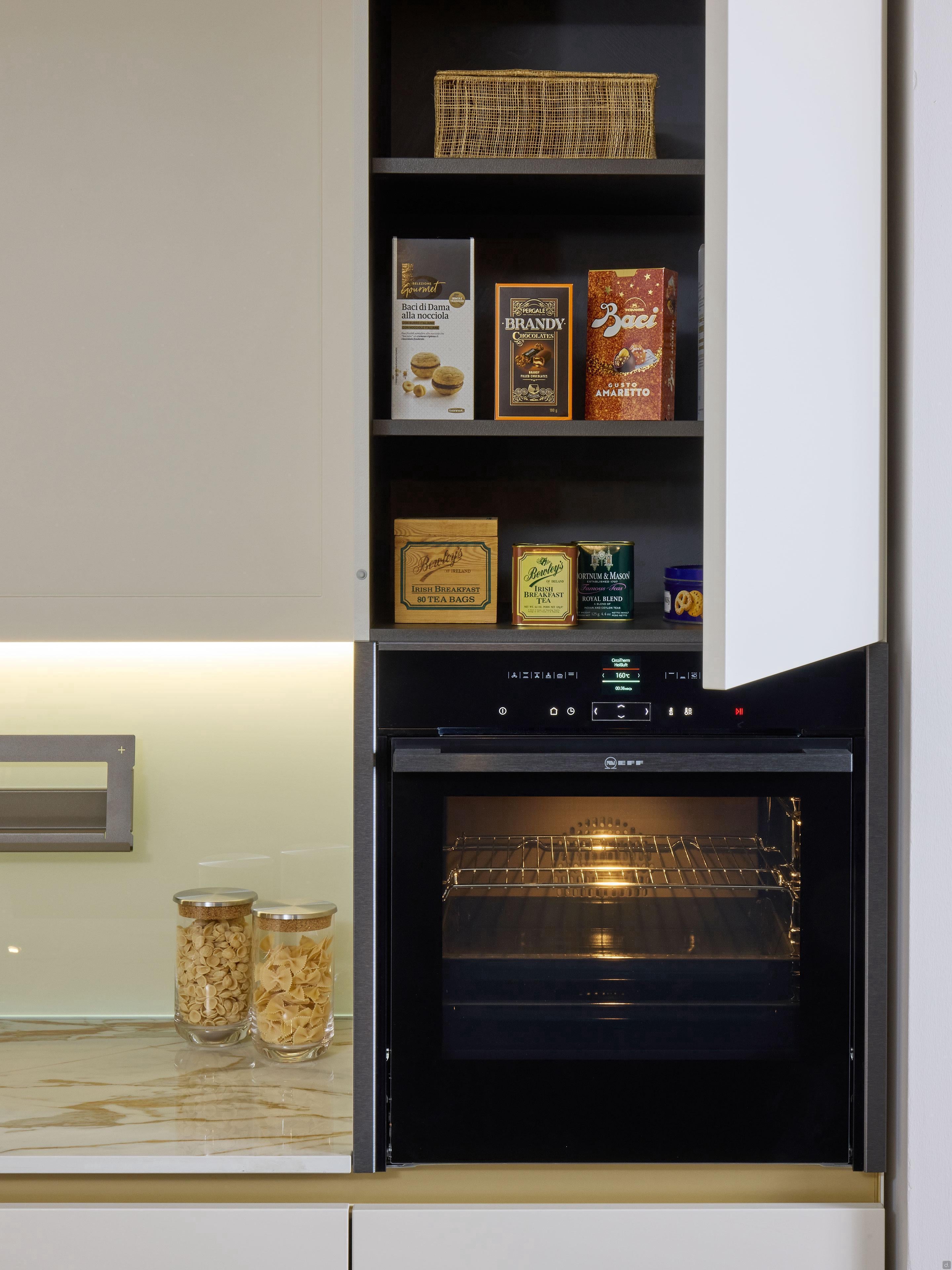 The Modern Kitchens by Kitchen Furniture in Yerevan features an open oven with the light on, shelves stocked with packaged food, and marble countertops displaying two glass jars of dried goods for a stylish, contemporary look.
