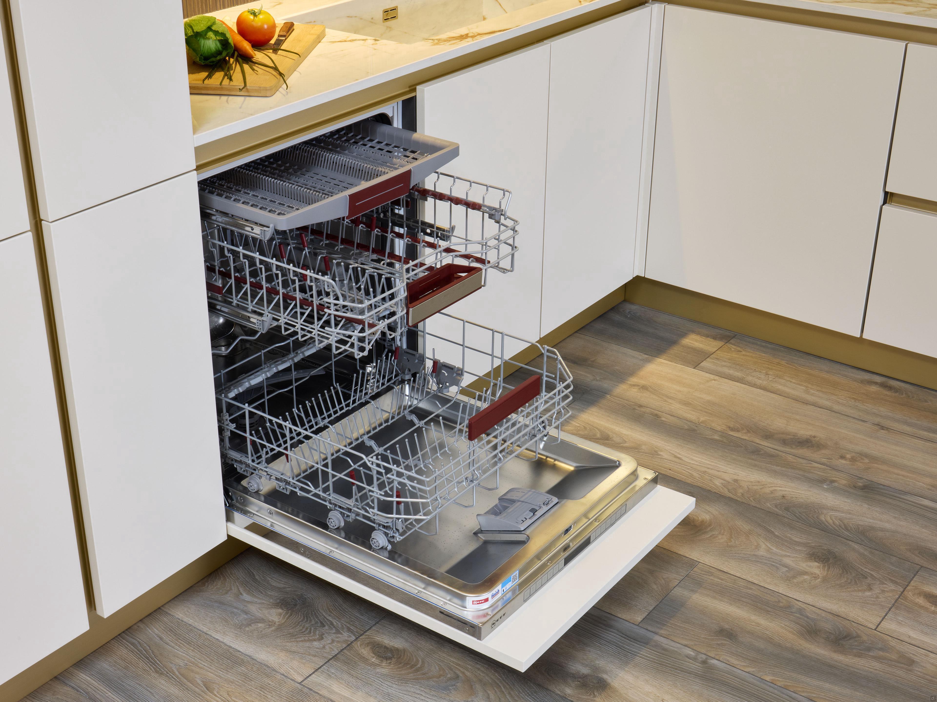 A Modern Kitchens built-in dishwasher by Kitchen Furniture stands open with empty racks and a cutlery tray, set in a space with white cabinets and wood flooring—ideal for highlighting stylish custom kitchen design.