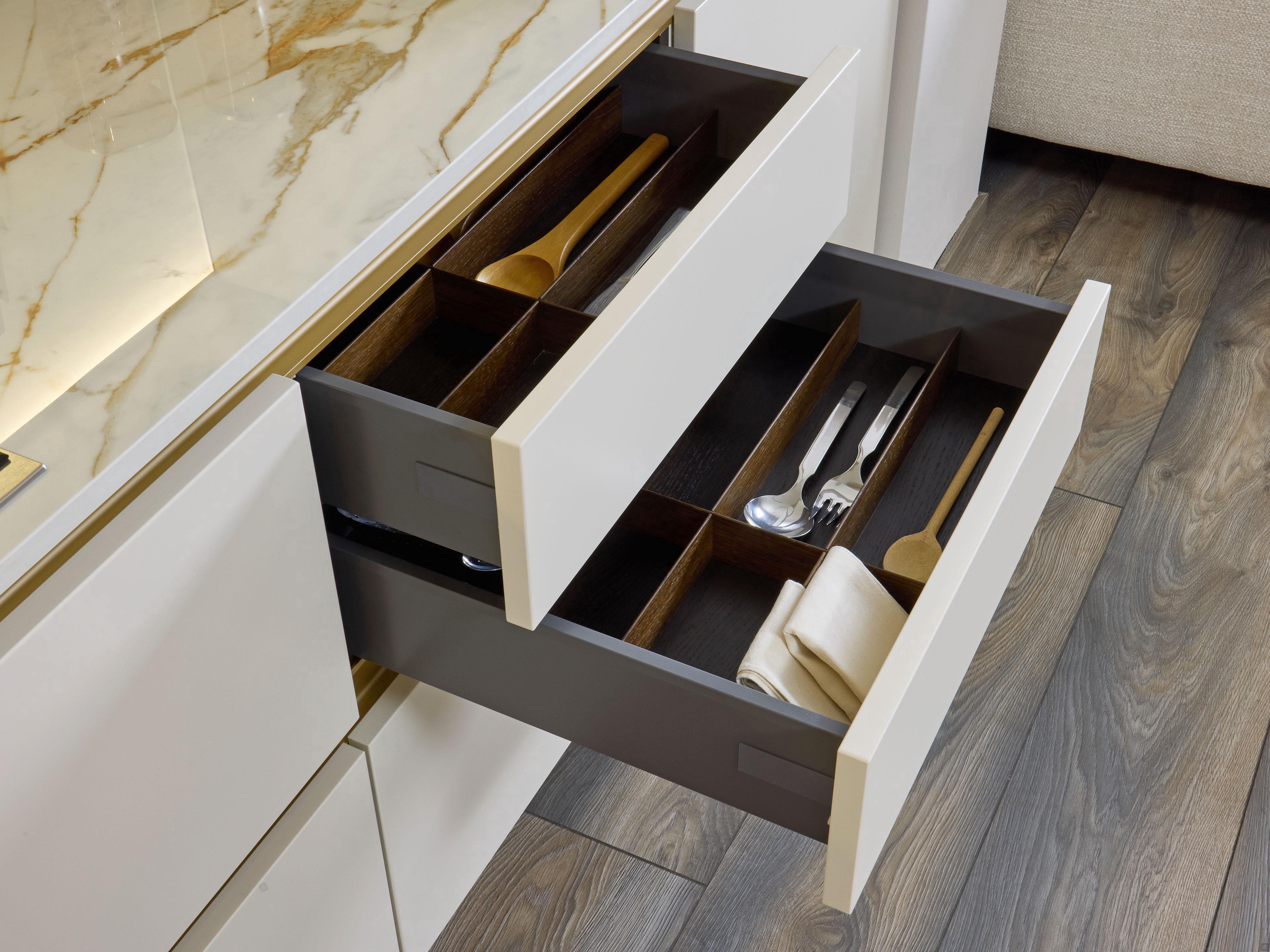Two open drawers with wooden dividers neatly organize utensils and a folded napkin, highlighting Kitchen Furniture's Modern Kitchens collection in Yerevan, complete with a sleek marble countertop.