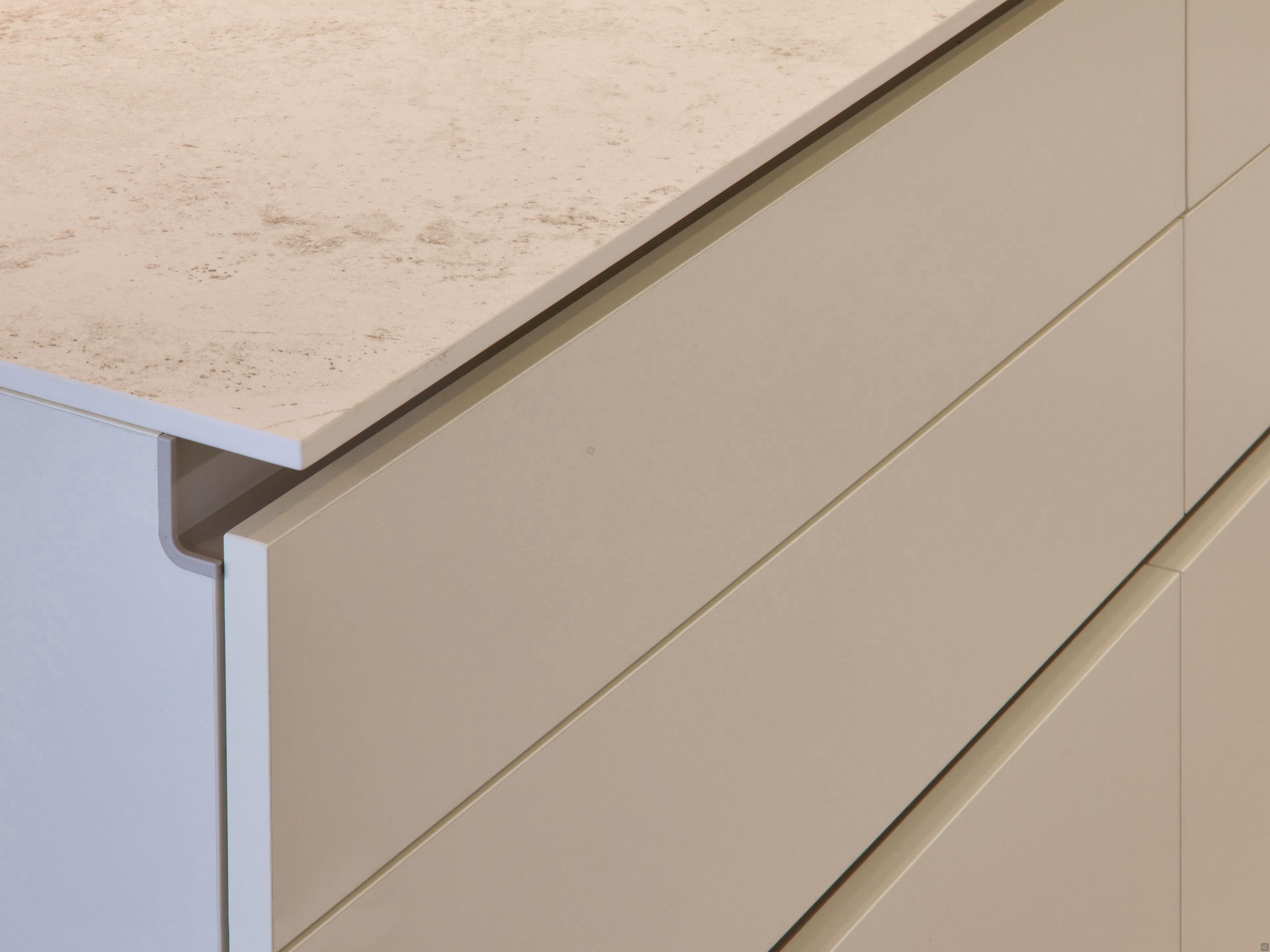 A close-up of Kitchen Furniture's Modern Kitchens showcases handleless beige cabinets with a light stone countertop, featuring clean lines and a minimalist design for custom kitchen furniture.
