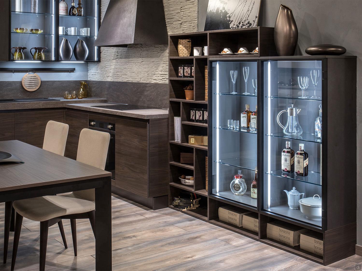Modern kitchen features dark wood cabinets, a four-seat dining table, glassware display, sleek surfaces, open shelves, and under-cabinet lighting. Custom kitchen furniture inspired by "Urban Kitchens" from ORDER Kitchen Furniture.