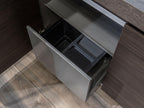 A modern Urban Kitchens drawer by ORDER Kitchen Furniture is open, showing a black plastic bin system for waste and recycling. Its sleek metallic front suits Yerevan's urban homes with dark cabinets and wood floors.