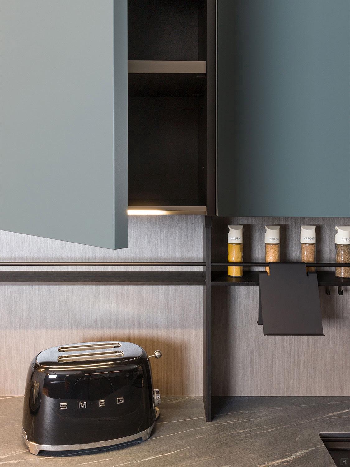 A modern kitchen with a black SMEG toaster on a gray countertop, blue cabinets, and neatly arranged spices—perfect inspiration for fans of Urban Kitchens by ORDER Kitchen Furniture in Yerevan.