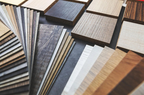 A range of wood laminate samples from ORDER Kitchen Furniture's Modern Kitchens collection are shown in a fan and grid layout, highlighting diverse colors and grains for custom kitchen designs.